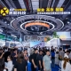 Crowded trade show floor with booths and a large circular illuminated structure overhead; attendees inspect displays around AP Systems booths.