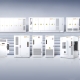 Row of white storage cabinets and battery enclosures on a tiered platform against a blue gradient backdrop.